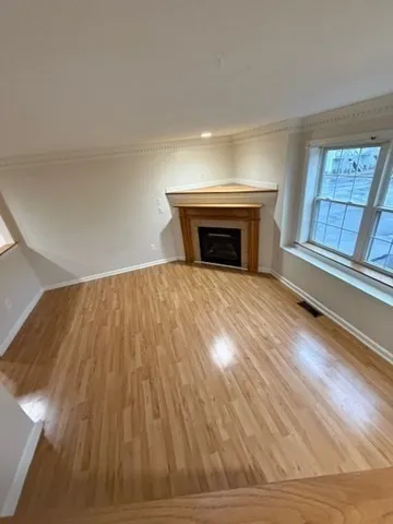 a view of empty room with wooden floor and fireplace
