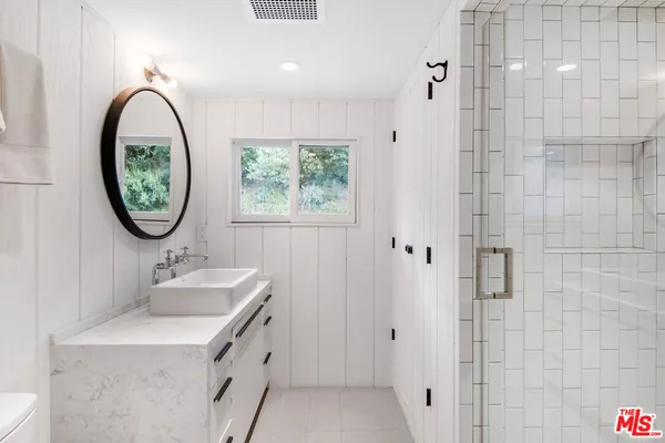 a bathroom with a granite countertop sink a mirror and a shower