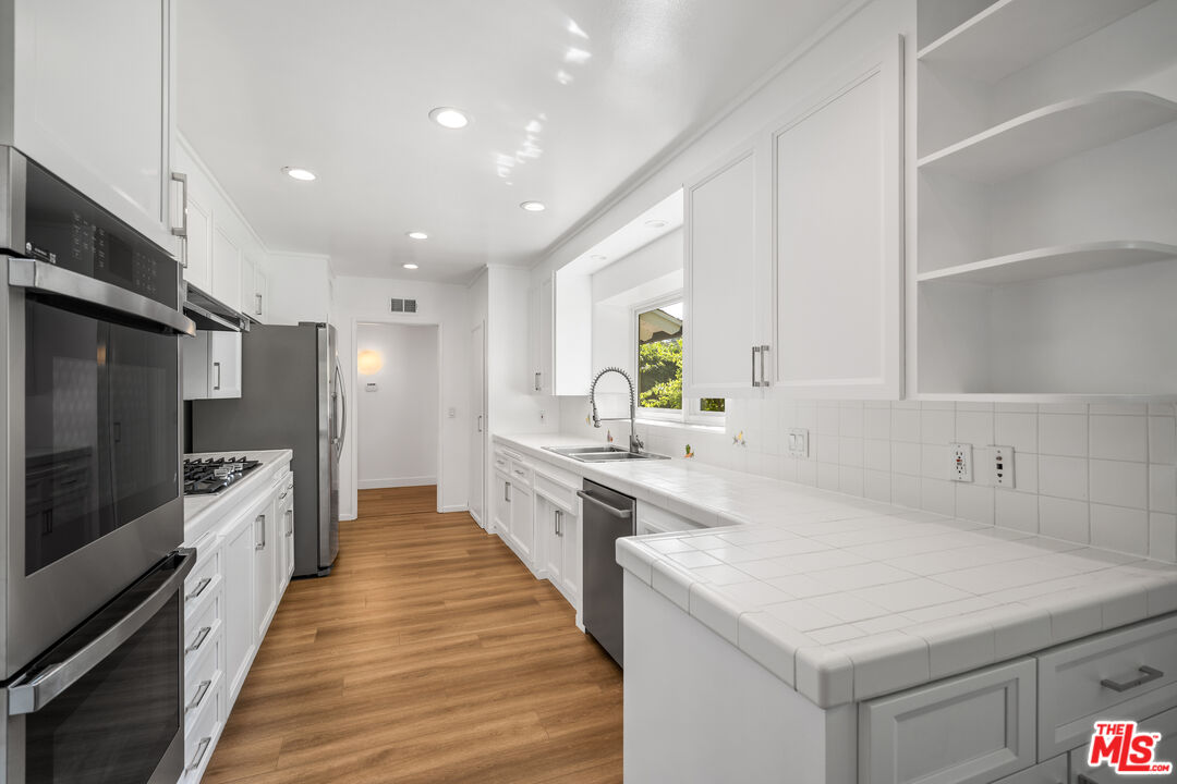 16849 Adlon Road Encino, CA 91436 - Photo 29 of 40 a large kitchen with stainless steel appliances a large counter top a stove a sink and a refrigerator