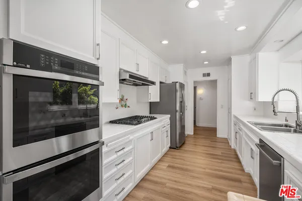 a kitchen with stainless steel appliances kitchen island granite countertop a stove a sink and a refrigerator