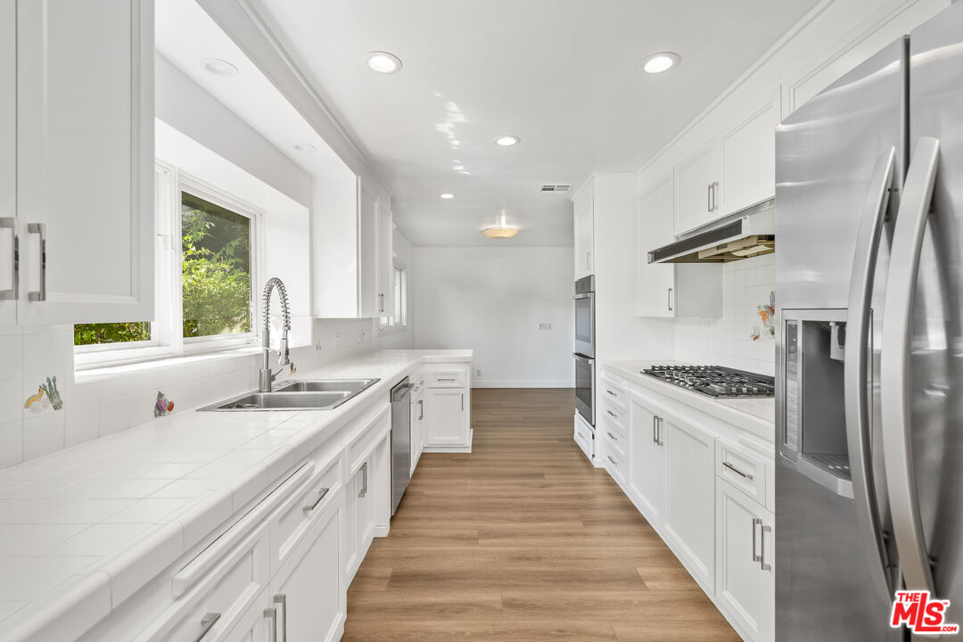 16849 Adlon Road Encino, CA 91436 - Photo 31 of 40 a large kitchen with stainless steel appliances granite countertop a lot of counter space and wooden floors
