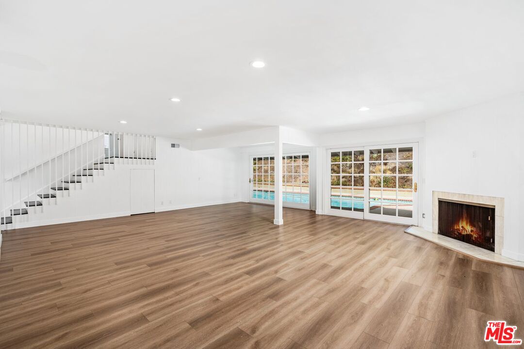 16849 Adlon Road Encino, CA 91436 - Photo 34 of 40 a view of an empty room with wooden floor fireplace and a window