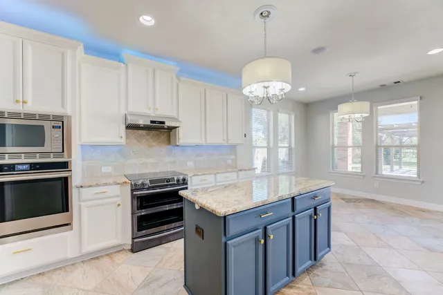 a kitchen with kitchen island granite countertop a stove and a sink with granite countertops