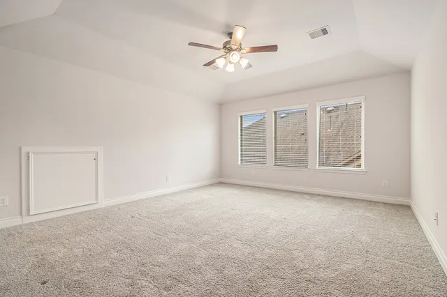 an empty room with windows and fan
