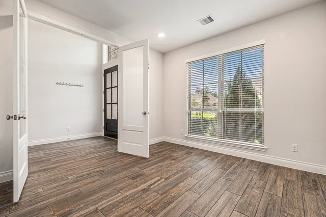 a view of an empty room with wooden floor and a window