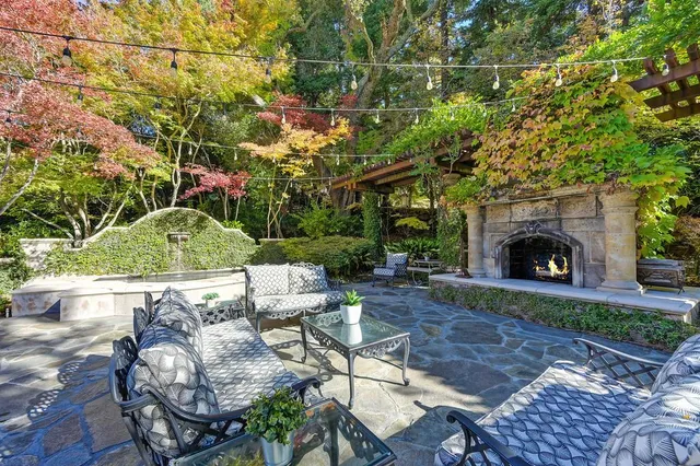 a view of backyard with seating space and trees in the background