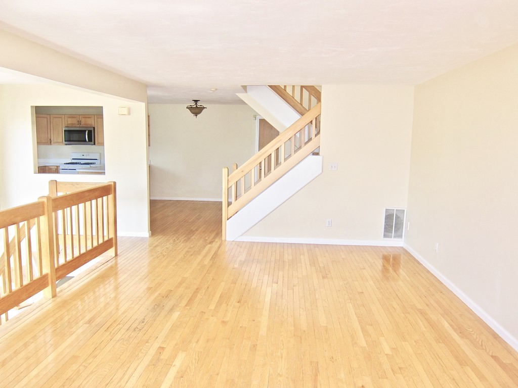 243 Captain Eames Circle, Unit 243 Ashland, MA 01721 - Photo 3 of 16 a view of a hallway with wooden floor and a living room