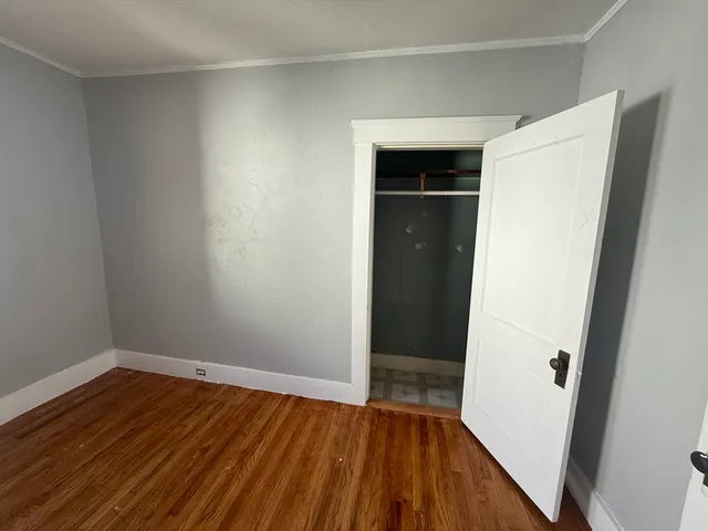 a view of an empty room with wooden floor and closet