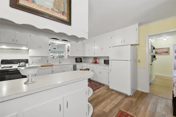 a kitchen with white cabinets and refrigerator