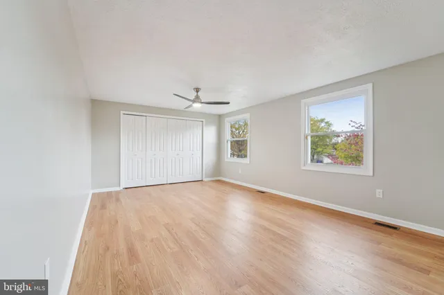 an empty room with wooden floor and windows