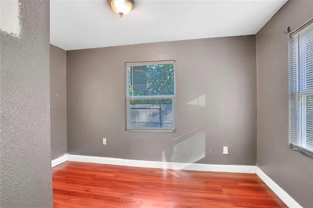 a view of an empty room with wooden floor and a window