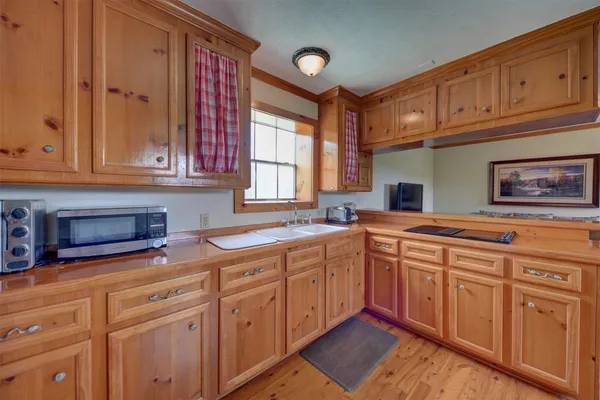a kitchen with stainless steel appliances granite countertop a refrigerator a sink dishwasher a stove and white countertops with wooden floor