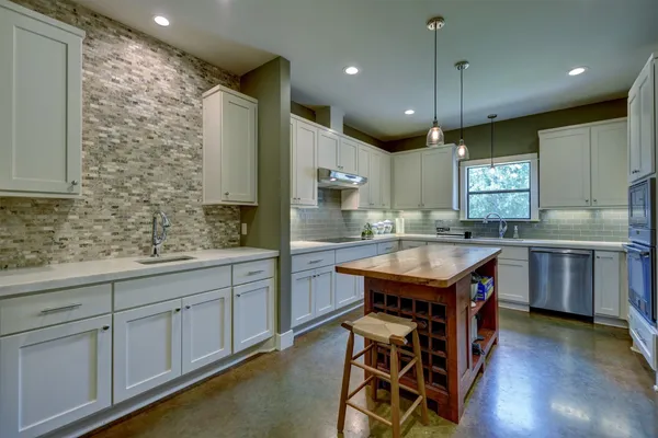 a kitchen with stainless steel appliances refrigerator cabinets dining table and chairs