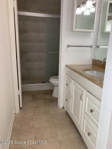 a bathroom with a granite countertop shower a toilet and a sink