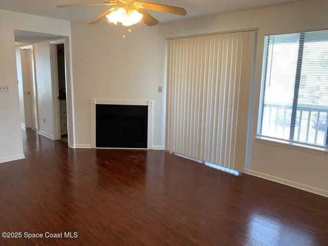 an empty room with wooden floor cabinet and windows