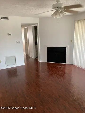 an empty room with wooden floor fireplace and windows