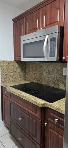 a kitchen with kitchen island granite countertop wooden cabinets and a sink