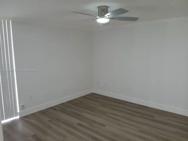 an empty room with wooden floor and ceiling fan