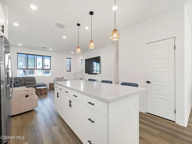 a kitchen with stainless steel appliances a sink a stove a refrigerator cabinets and a dining table