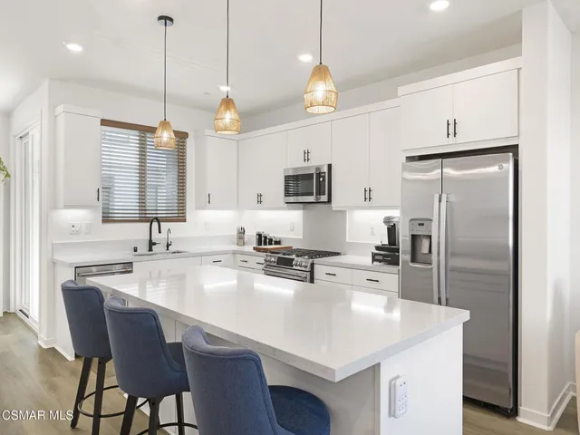 a kitchen with stainless steel appliances granite countertop a sink a stove a refrigerator and island