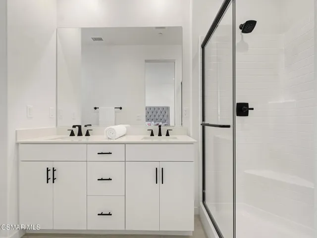 a bathroom with a double vanity sink mirror and shower