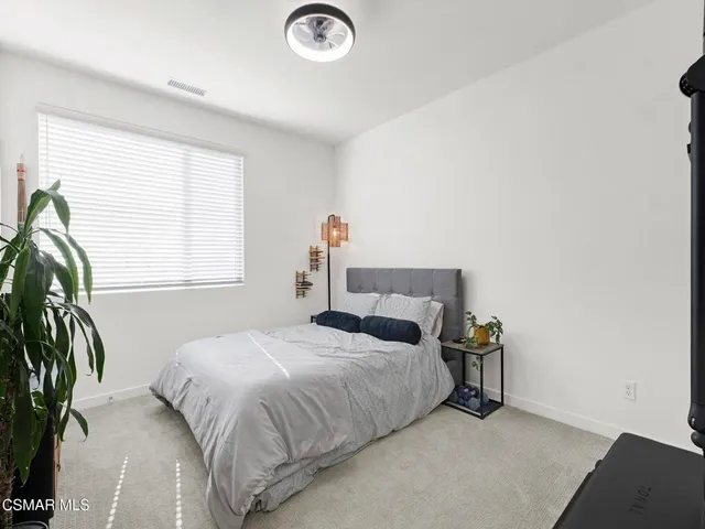a bedroom with a bed and a flat tv screen on dresser