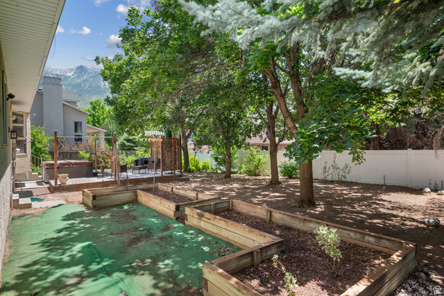1726 Wasatch Boulevard Sandy, UT 84092 - Photo 28 of 38 Expansive backyard featuring multiple raised garden beds, mature trees, and a privacy fence