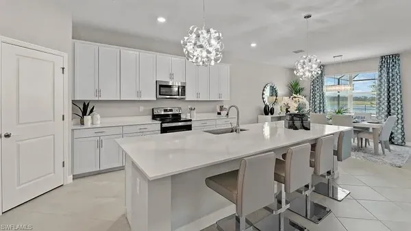 a kitchen that has a lot of white cabinets and stainless steel appliances
