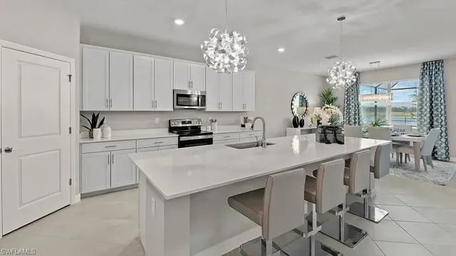 a kitchen that has a lot of white cabinets and stainless steel appliances