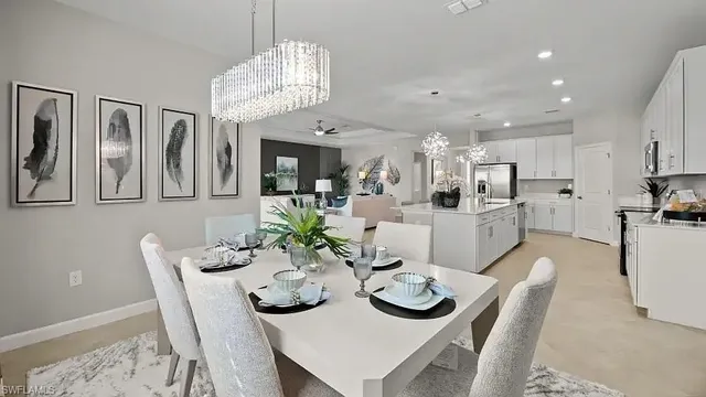 a view of a dining room and livingroom with furniture a rug a kitchen and chandelier