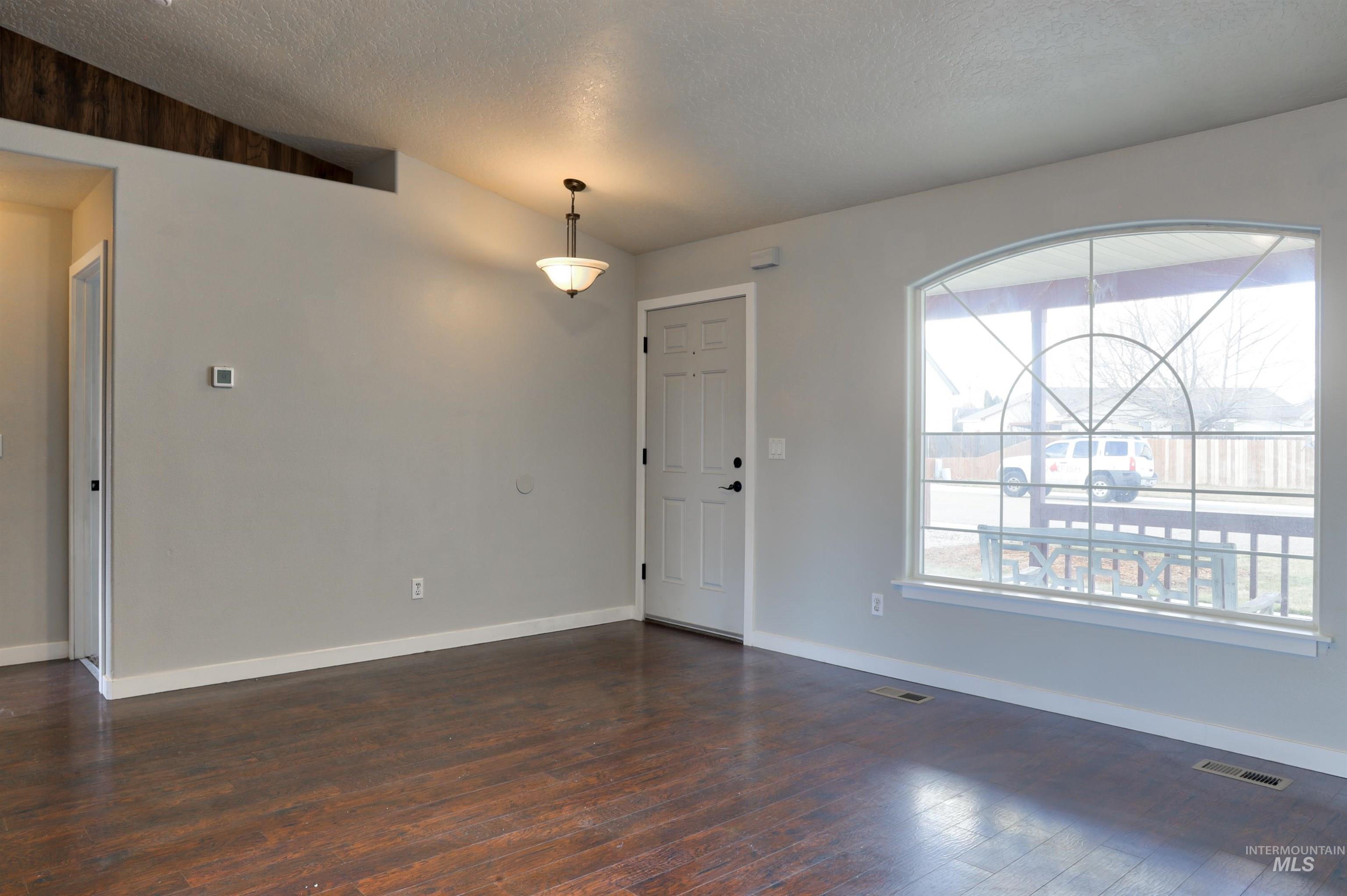 4911 Buffalo Grass Avenue Caldwell, ID 83607 - Photo 4 of 15 Empty room featuring lofted ceiling, a textured ceiling, and dark wood finished floors