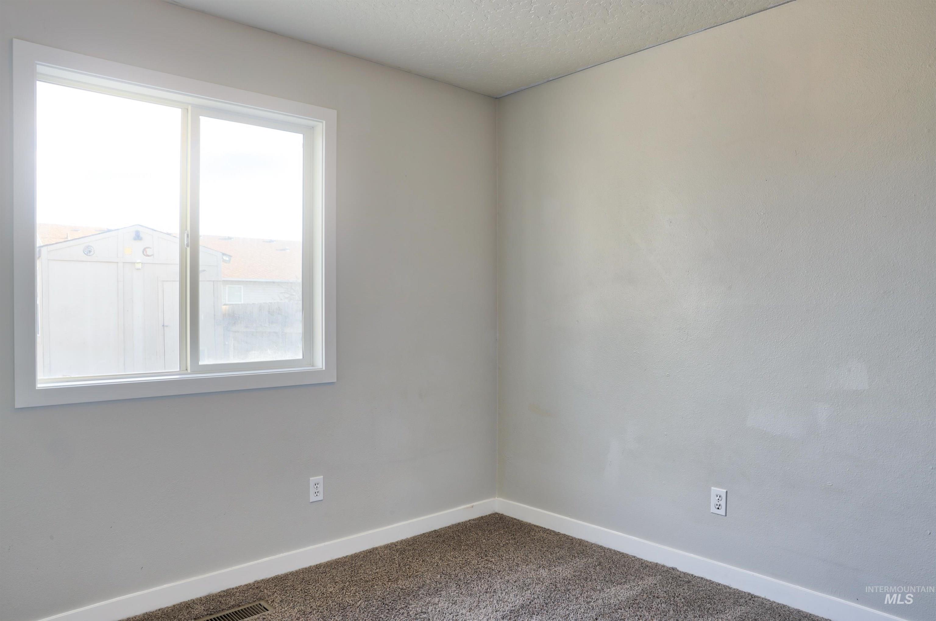 4911 Buffalo Grass Avenue Caldwell, ID 83607 - Photo 8 of 15 Empty room with carpet floors and a textured ceiling