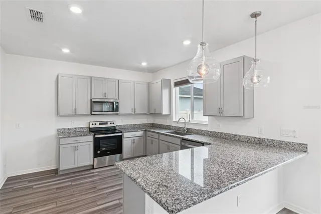a kitchen with stainless steel appliances granite countertop a sink a stove and a wooden floors