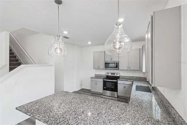 a kitchen with stainless steel appliances granite countertop a sink a stove and a refrigerator