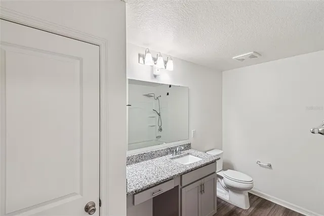 a bathroom with a granite countertop sink a toilet and a mirror