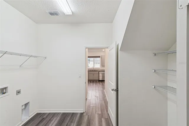 a view of a hallway with wooden floor and a bathroom