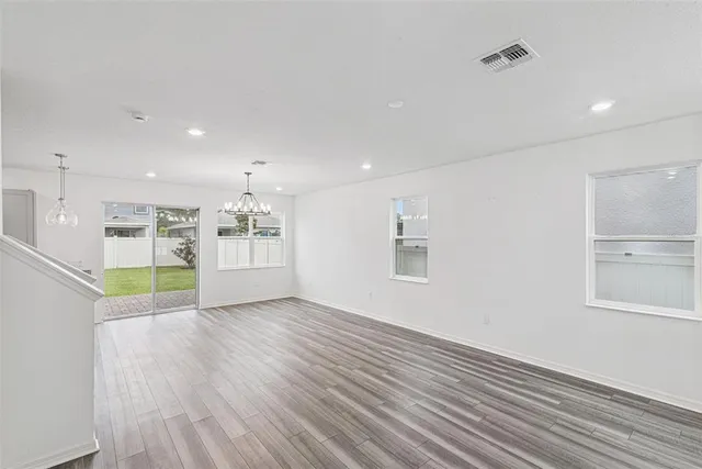 a view of an empty room with window and wooden floor