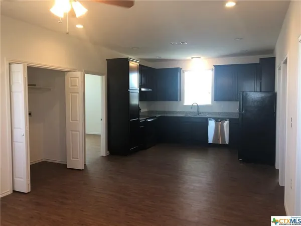 a kitchen with stainless steel appliances kitchen island granite countertop a refrigerator and a sink