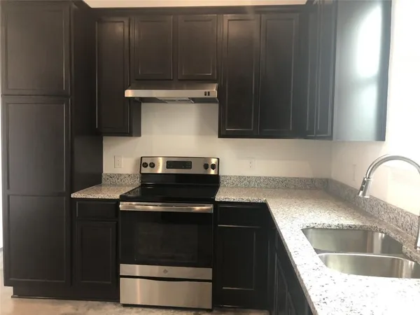 a kitchen with granite countertop a stove and a sink