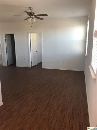 an empty room with windows and fan