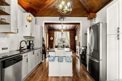 a kitchen with stainless steel appliances kitchen island granite countertop a stove a sink dishwasher and a refrigerator