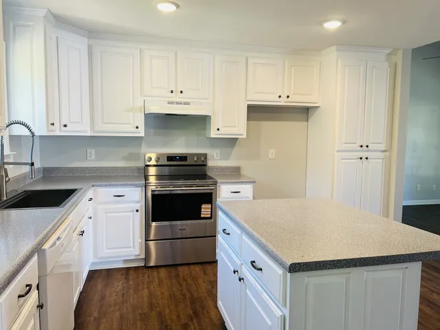 a kitchen with granite countertop white cabinets and white appliances