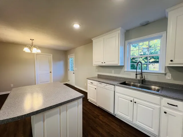 a kitchen with granite countertop white cabinets and window