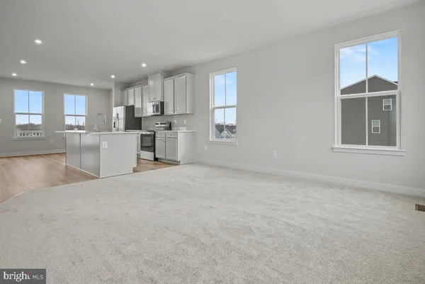 a large kitchen with kitchen island a stove a sink a refrigerator and white cabinets with wooden floor