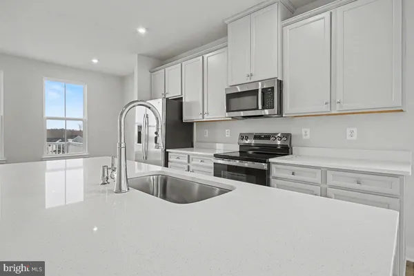 a kitchen with stainless steel appliances granite countertop a refrigerator sink and white cabinets