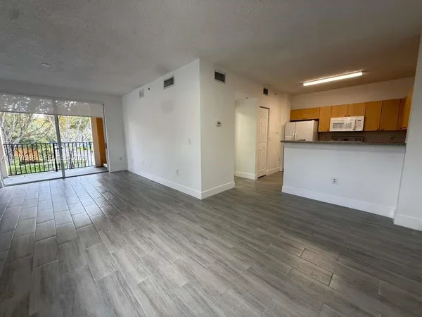 a view of a kitchen with wooden floor and a window