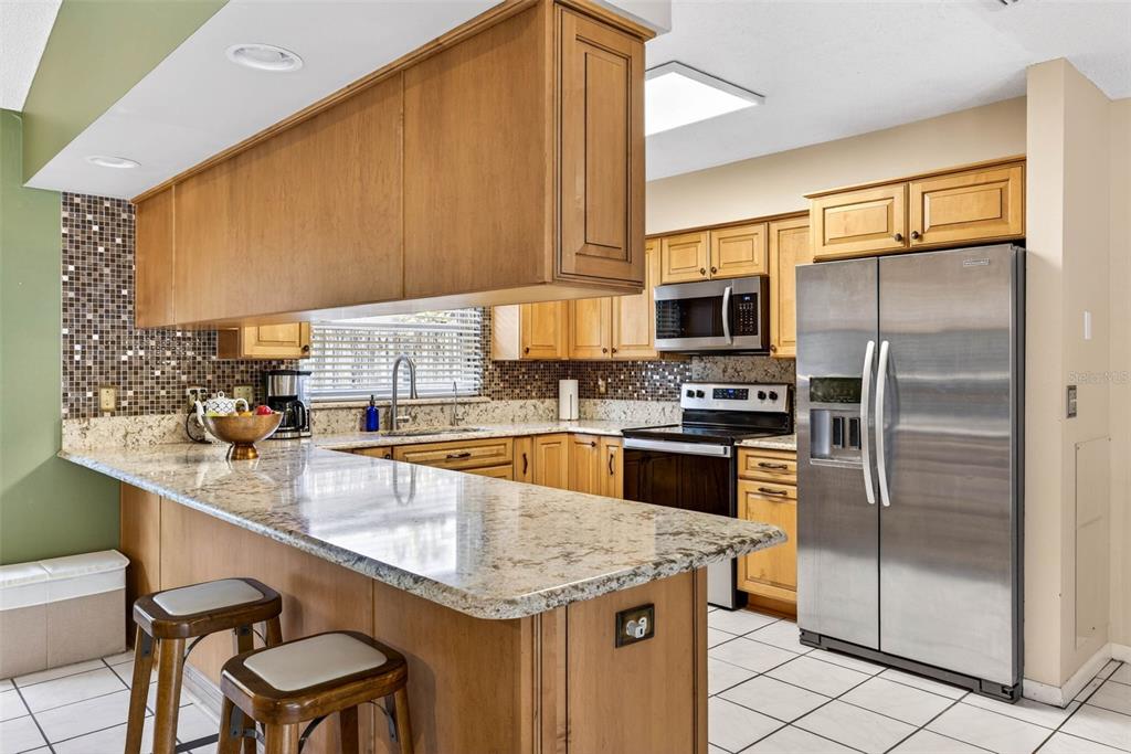 12913 Rain Forest Street Temple Terrace, FL 33617 - Photo 27 of 63 a kitchen with stainless steel appliances a sink a counter top space cabinets and a window