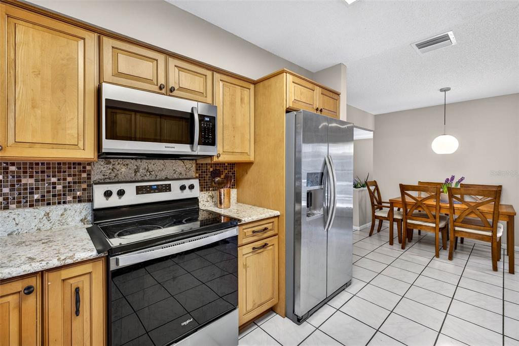 12913 Rain Forest Street Temple Terrace, FL 33617 - Photo 29 of 63 a kitchen with stainless steel appliances granite countertop a stove a sink and a microwave