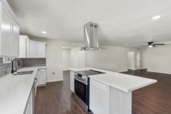 a kitchen that has a sink a stove and a wooden floor