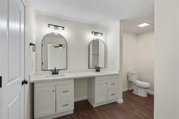 a bathroom with double vanity sinks a toilet a vanity and mirror